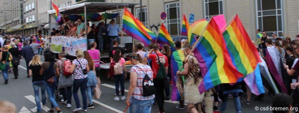 Ein Auszug von der CSD-Bremen-Demo 2017 mit mehreren Träger*innen der Regenbogenflagge.